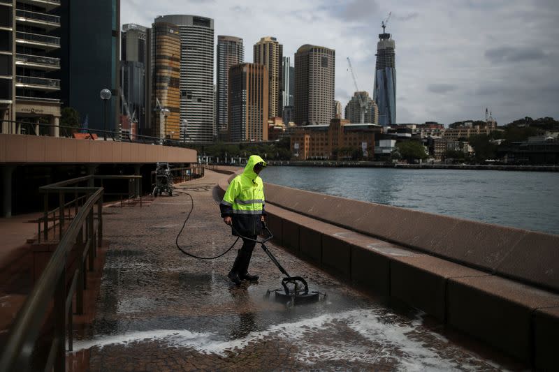 A worker cleans the waterfront area of the Sydney Opera House