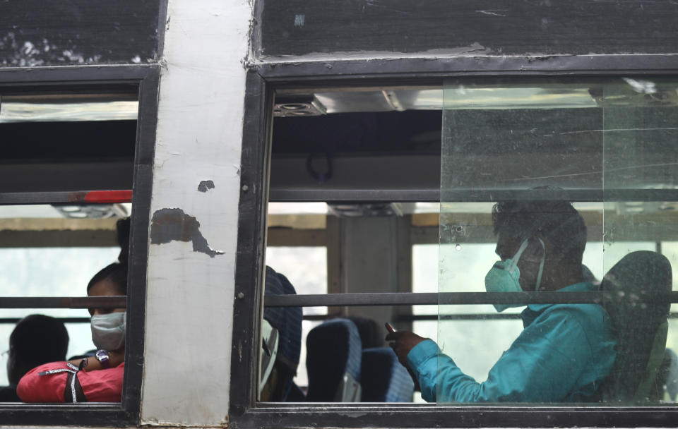 Commuters wear pollution masks and ride in a bus as the city is enveloped under thick smog in New Delhi, India, Tuesday, Nov. 12, 2019. A thick haze of polluted air is hanging over India's capital, with authorities trying to tackle the problem by sprinkling water to settle dust and banning some construction. The air quality index exceeded 400, about eight times the recommended maximum. (AP Photo/Manish Swarup)