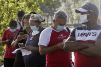 Patrons wait in line for the auto tag agency to open in Deerfield Beach, Fla., Thursday, July 2, 2020. A new rule went into effect in Broward County Thursday requiring facial coverings outdoors where social distancing is not possible. (Joe Cavaretta/South Florida Sun-Sentinel via AP)