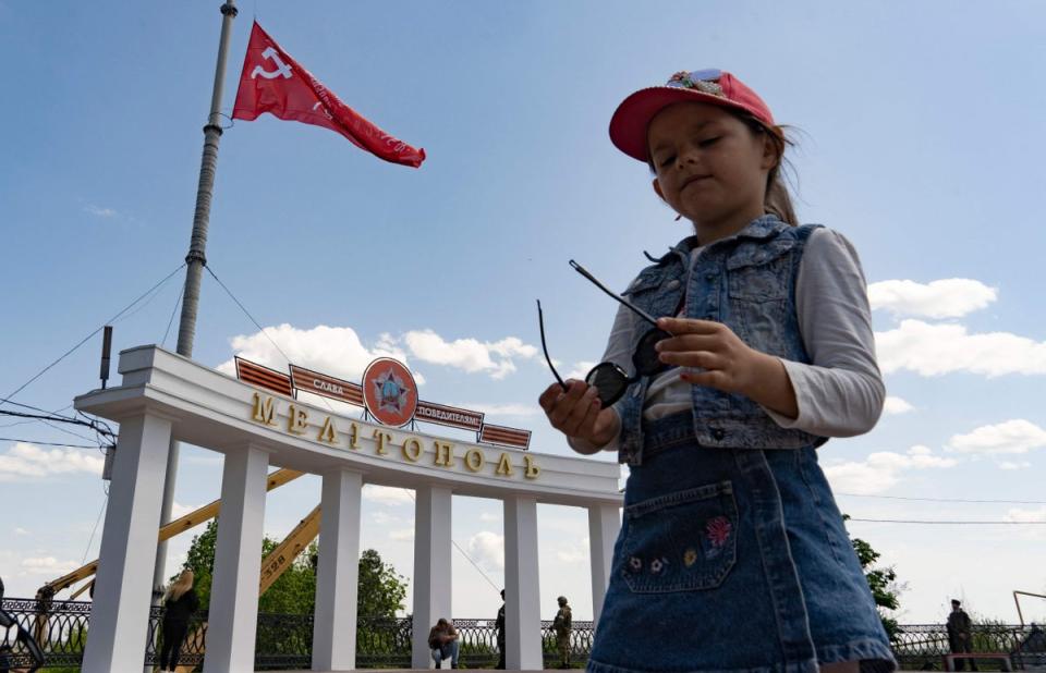 A girl stands near the Melitopol arch decorated with a red flag, St George ribbon and Soviet Second World War-era medal with the slogan ‘Glory to the victors!’  (AFP/Getty)