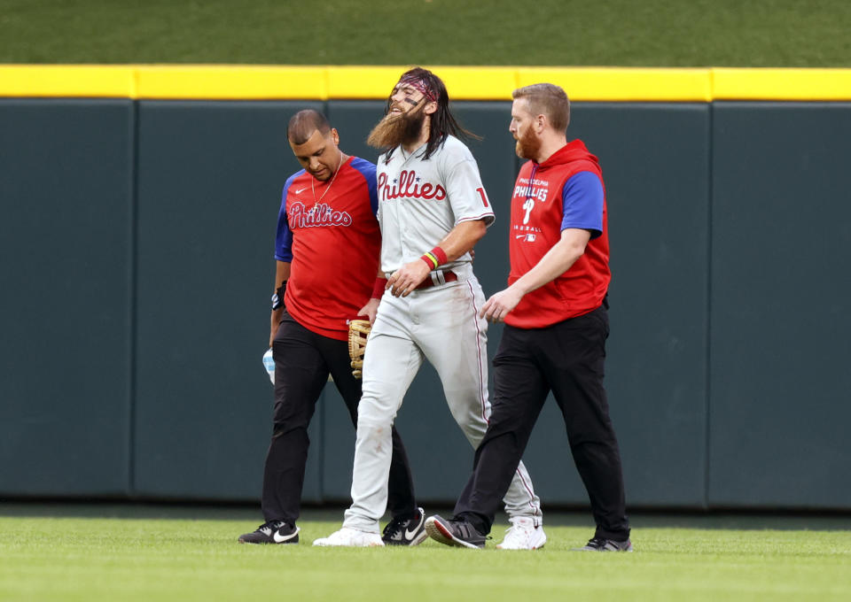 Philadelphia Phillies center fielder Brandon Marsh, center, is helpd off the field during the third inning of the team's baseball game against the Cincinnati Reds in Cincinnati on Tuesday, Aug. 16, 2022. (AP Photo/Paul Vernon)