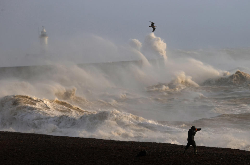 A person takes photographs of the sea as waves crash against the breakwater in Newhaven on January 2, 2024, as Storm Henk was set to bring strong winds and heavy rain across much of southern England. (Photo by ADRIAN DENNIS / AFP) (Photo by ADRIAN DENNIS/AFP via Getty Images)