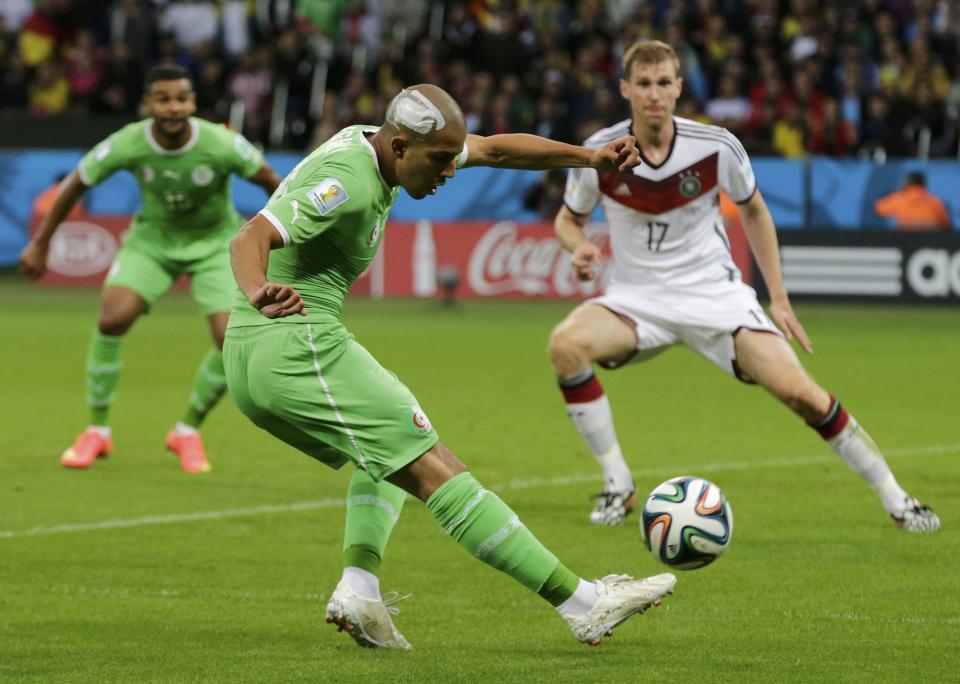 Algeria's Sofiane Feghouli kicks the ball past Germany's Per Mertesacker (R) but misses a chance to score a goal, during their 2014 World Cup round of 16 game at the Beira Rio stadium in Porto Alegre June 30, 2014. REUTERS/Henry Romero