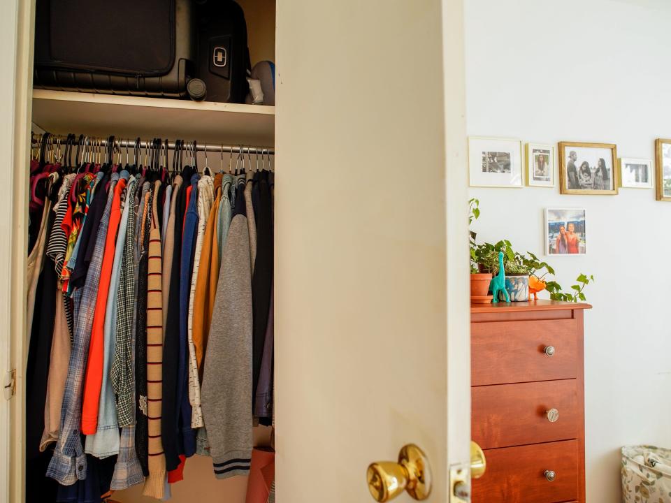 The authors closet open with mulit-colored clothes hanging inside