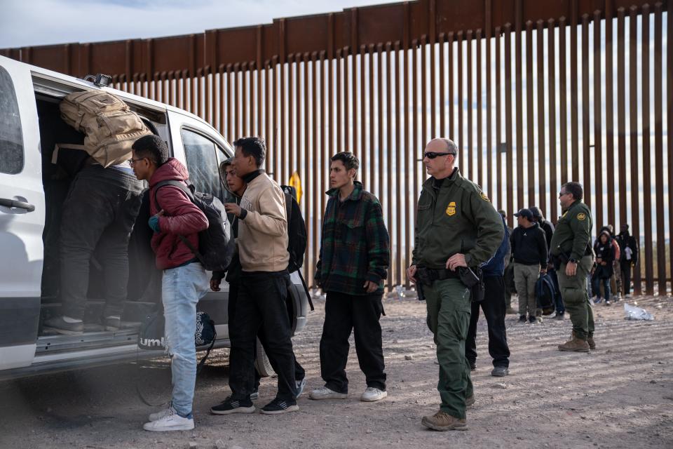 Migrants and asylum seekers are guided into vans to be transported for processing by U.S. Border Patrol agents in Organ Pipe Cactus National Monument along the U.S.-Mexico border about a mile west of Lukeville, Ariz., on Dec. 4, 2023. The Lukeville Port of Entry was closed indefinitely by officials Dec. 4.