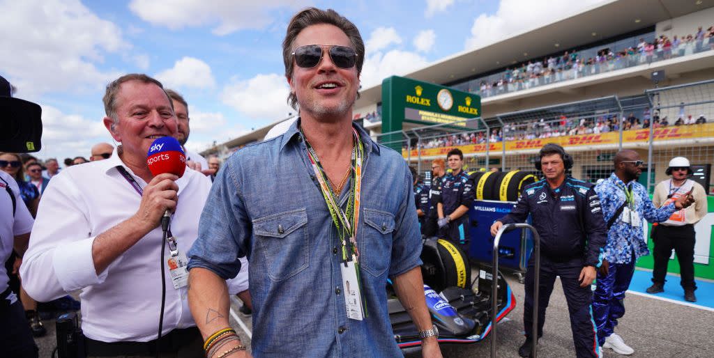 brad pitt walking along the f1 grid prior to a race with a reporter next to him