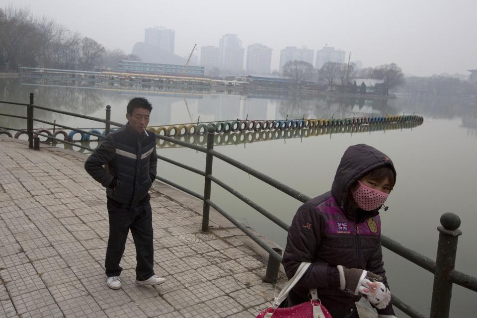 Residents walk around a lake during a day of heavy pollution in Beijing, China, Sunday, Feb. 23, 2014. (AP Photo/Ng Han Guan)