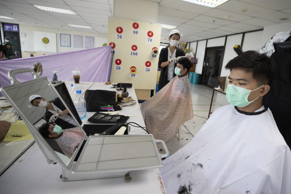 In this Tuesday, April 28, 2020, photo, volunteers of hairdressers give haircuts to medical workers treating COVID-19 patients at Bangkok Metropolitan Administration General Hospital in Bangkok, Thailand. Hairstylest Pornsupa Hattayong, 43, is boosting the morale of frontline medical workers by dispensing free haircuts at Bangkok hospitals since Thailand’s hair salons have been closed for more than a month, to help stop the spread of the coronavirus. (AP Photo/Sakchai Lalit)