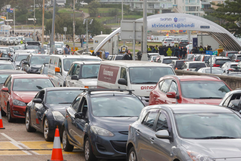 Cars line up along Campbell Parade as health workers congregate ahead of the opening of the COVID-19 testing clinic at Bondi Beach.