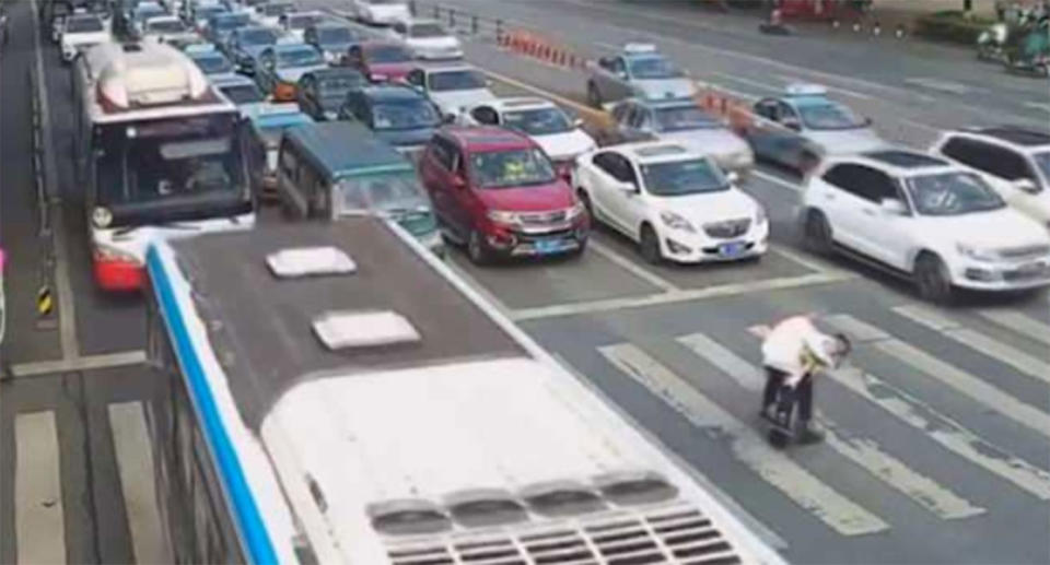 The officer carries the elderly man on his back, allowing stopped traffic to continue across the intersection. Source: Weibo / Mianyang Police