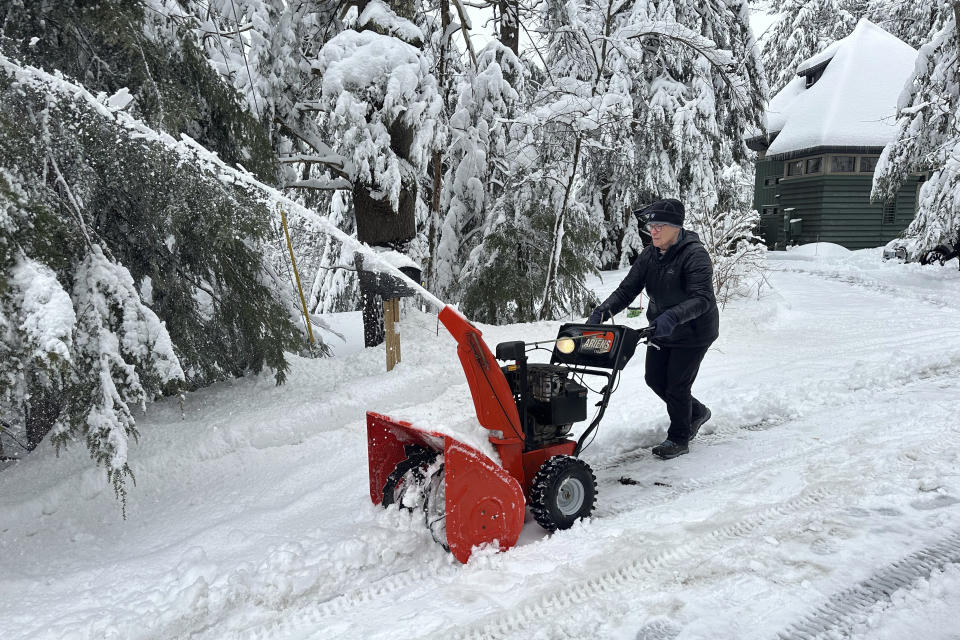 Betty Tidd, 78, clears snow Friday, April 5, 2024, in Gilford, N.H. Tidd lost power early Thursday but she and her husband have been staying comfortable thanks to their backup battery system and propane stove. (AP Photo/Nick Perry)