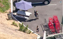 <p>A Los Angeles Police officer carries a child as another runs ahead of him after a pursuit, and the driver ran into a nearby Trader Joe’s supermarket, starting a hostage situation in the Silverlake district of Los Angeles Saturday. (Photo: KNBC-TV via AP) </p>