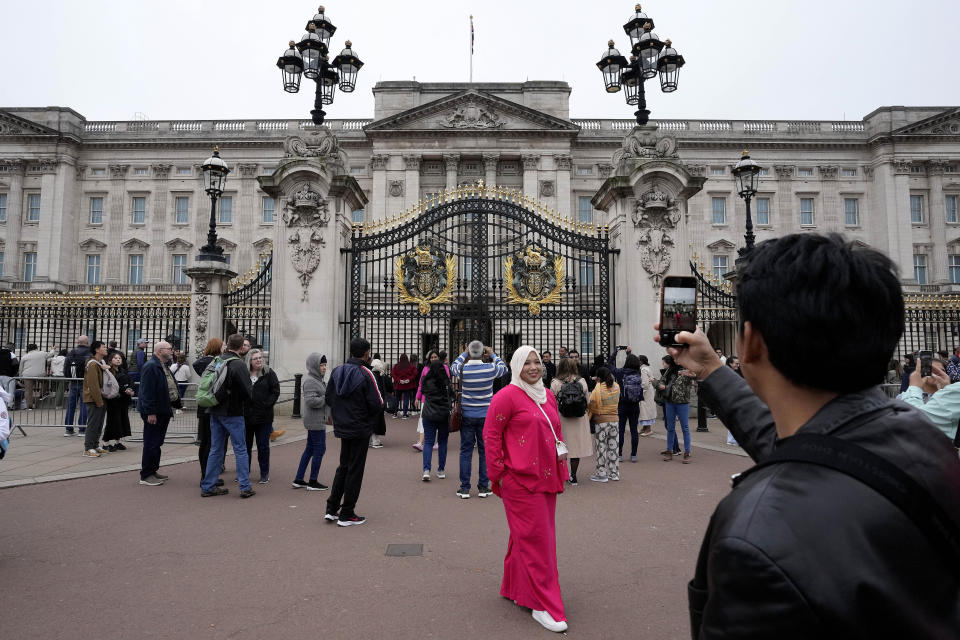 FILE - Tourists take pictures as they visit Buckingham Palace in London, Tuesday, May 2, 2023. The coronation of King Charles III will takes place at Westminster Abbey on May 6. Officials are expecting to see a tourism boost and there is no shortage of coronation-themed events and commemorative products that could ring up additional sales taxes. (AP Photo/Frank Augstein, File)