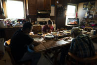 Molly Snell, center, says grace with her partner, Tyler Weyiouanna, foreground left, Weyiouanna's grandfather, Clifford, as they gather around a dinner table to celebrate Tyler's 31st birthday in Shishmaref, Alaska, Saturday, Oct. 1, 2022. (AP Photo/Jae C. Hong)