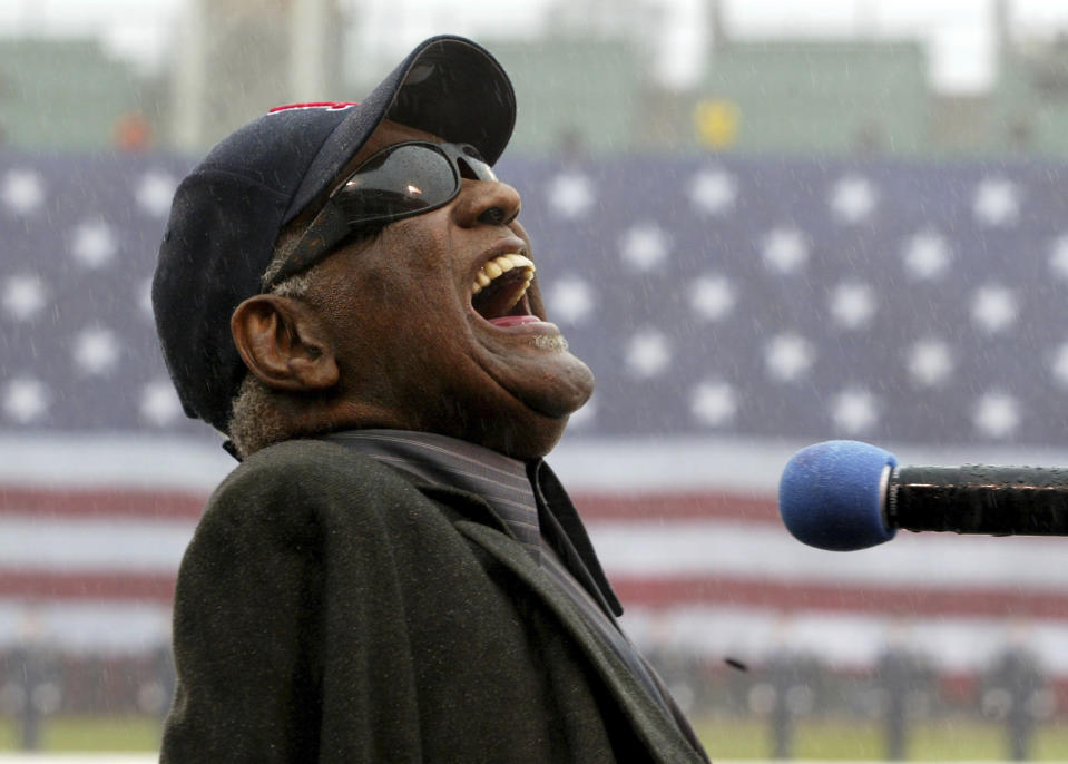 FILE - Ray Charles sings "America The Beautiful," in the rain at Fenway Park in Boston, April 11, 2003. Charles will be posthumously inducted into the Country Music Hall of Fame on Sunday, May 1, 2022, in Nashville, Tenn., along with The Judds. The ceremony will continue despite the death Saturday of Naomi Judd, who performed with daughter Wynonna as The Judds. (AP Photo/Winslow Townson, File)