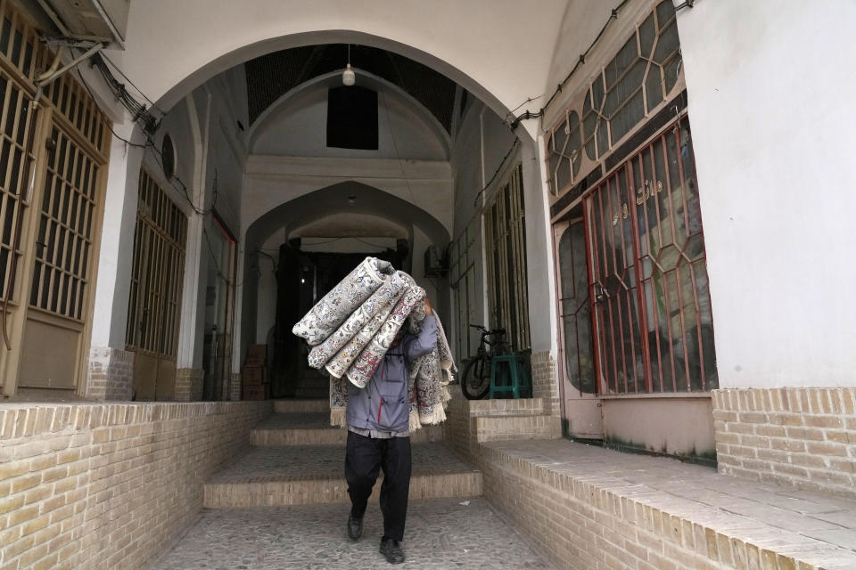 A worker carries carpets at the traditional bazaar of the city of Kashan, about 152 miles (245 km) south of the capital Tehran, Iran, Tuesday, April 30, 2024. (AP Photo/Vahid Salemi)