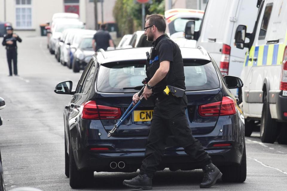 A police officer carries bolt cutters outside a Newport house being searched after three men were arrested in connection with an explosion on the London Underground (REUTERS)