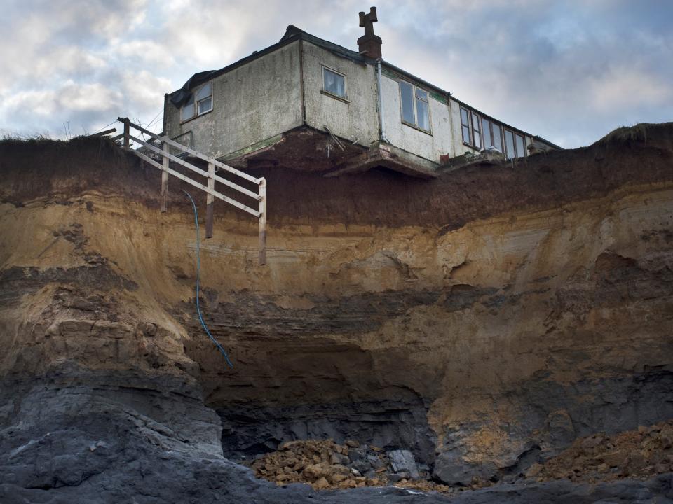 House on edge of cliff after erosion from Storm damage, North Sea storm surge December 5, 2013, Happisburgh, Norfolk UK.