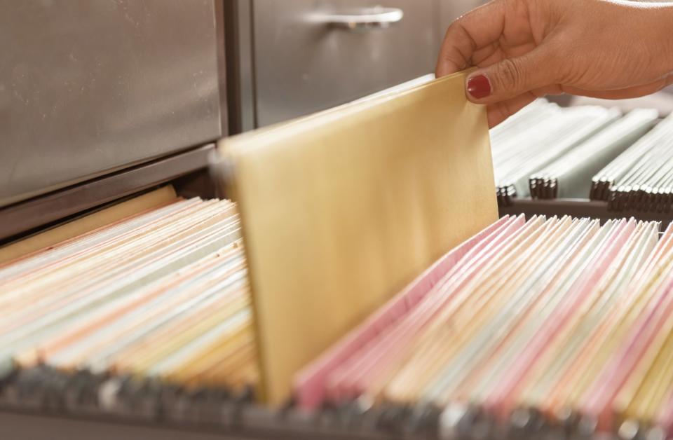 hand pulling file out of filing cabinet drawer