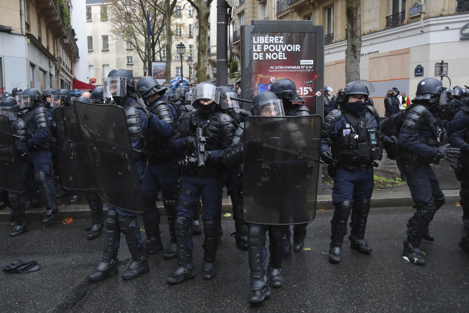 Riot police officers take position during a protest against a proposed bill , Saturday, Dec.12, 2020 in Paris. The bill's most contested measure could make it more difficult for people to film police officers. It aims to outlaw the publication of images with intent to cause harm to police. The provision has caused such an uproar that the government has decided to rewrite it. Critics fear the law could erode press freedom and make it more difficult to expose police brutality. (AP Photo/Thibault Camus)