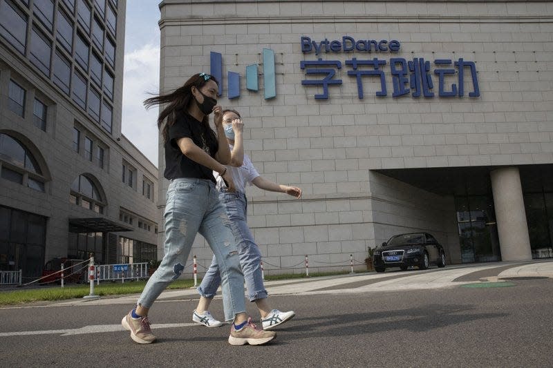 FILE - In this Aug. 7, 2020, file photo, women wearing masks to prevent the spread of the coronavirus chat as they pass by the headquarters of ByteDance, owners of TikTok, in Beijing, China. TikTok's owner said Thursday, Sept. 24, 2020, that it has applied for a Chinese technology export license as it tries to complete a deal with Oracle and Walmart to keep the popular video app operating in the United States.