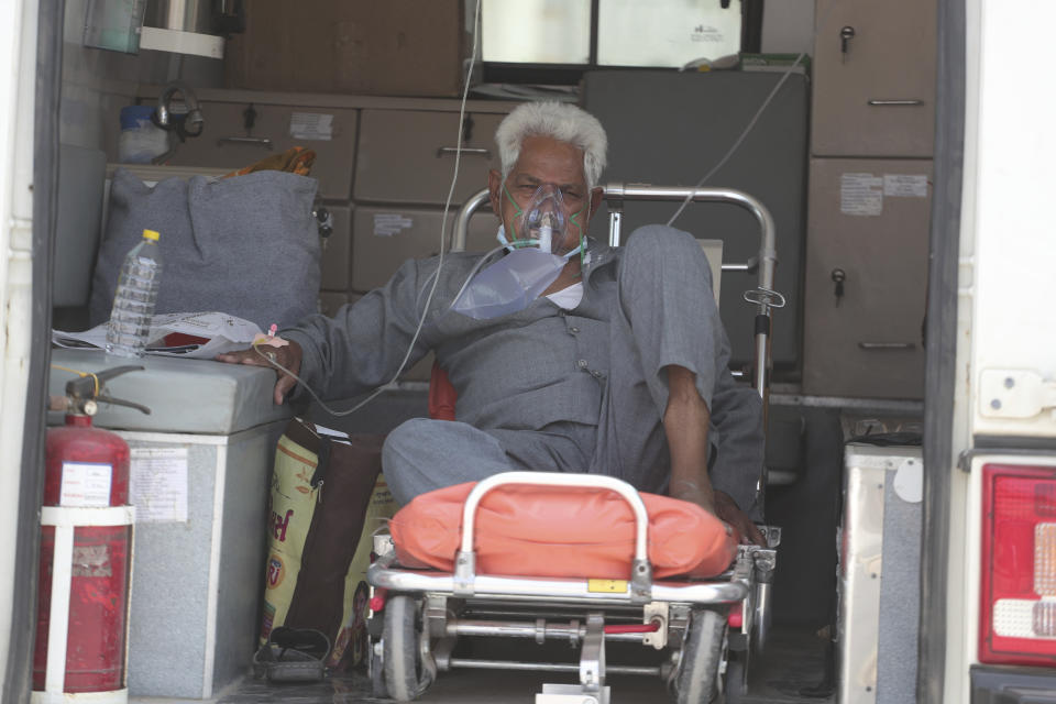 A COVID-19 patient waits inside an ambulance to be attended to and admitted into a dedicated COVID-19 government hospital in Ahmedabad, India, Thursday, April 22, 2021. A fire killed 13 COVID-19 patients in a hospital in western India early Friday as an extreme surge in coronavirus infections leaves the nation short of medical care and oxygen. India reported another global record in daily infections for a second straight day Friday, adding 332,730 new cases. The surge already has driven its fragile health systems to the breaking point with understaffed hospitals overflowing with patients and critically short of supplies. (AP Photo/Ajit Solanki)