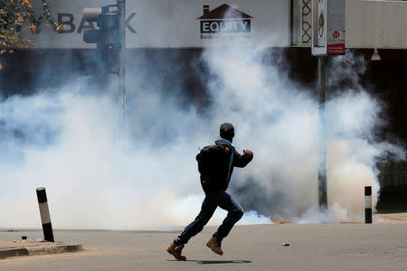 A protester runs away from tear gas during a protest by opposition supporters against against the retention of the election officials they blame for last month's botched elections, in Nairobi, Kenya October 2, 2017. REUTERS/Thomas Mukoya
