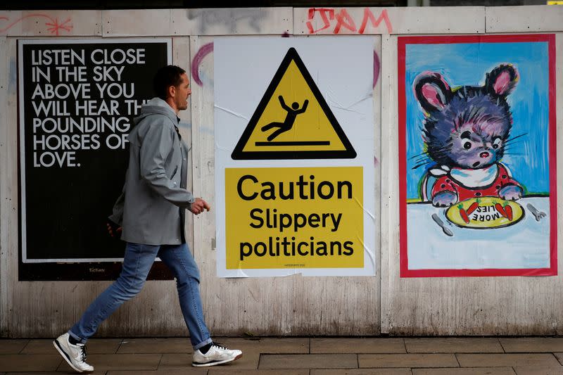 A man walks past posters following the outbreak of the coronavirus disease (COVID-19), in Manchester, Britain