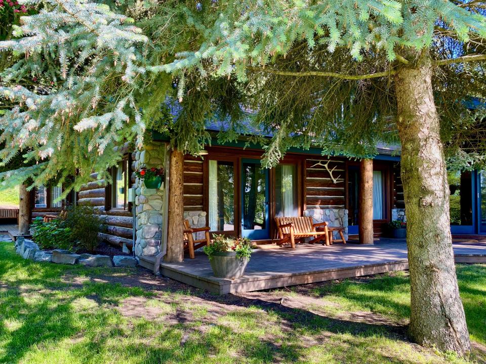 A rustic log cabin in the woods with trees and a porch.