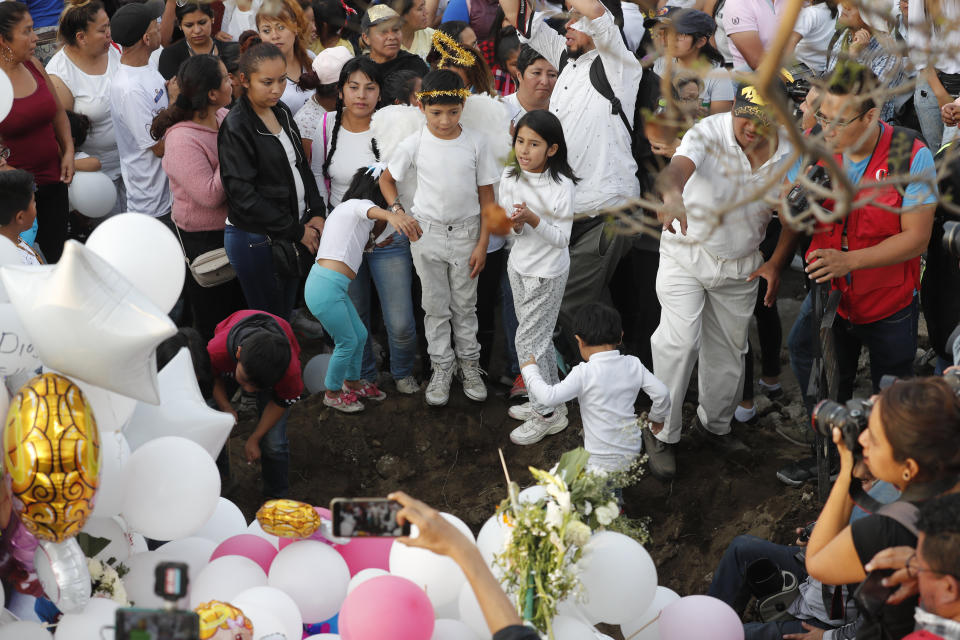 Children sing next to the grave of 7-year-old murder victim Fatima in Mexico City, Tuesday, Feb. 18, 2020. Fatima's body was found wrapped in a bag and abandoned in a rural area on Saturday. Five people have been questioned in the case, and video footage of her abduction exists. (AP Photo/Marco Ugarte)