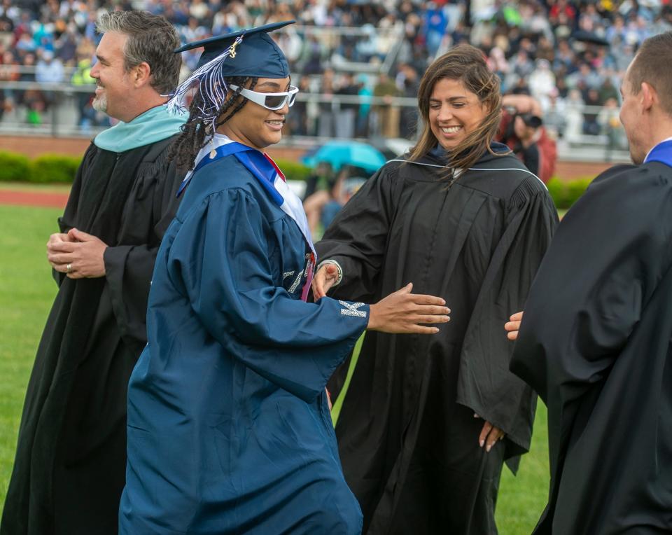 As Framingham High School senior Jennifer Candelario Soto is about to get her diploma, she shakes hands with, from left, Superintendent of Schools Robert Tremblay, state Rep. and School Committee Chair Priscila Sousa and Vice Principal Jon Kanavich, June 4, 2023.