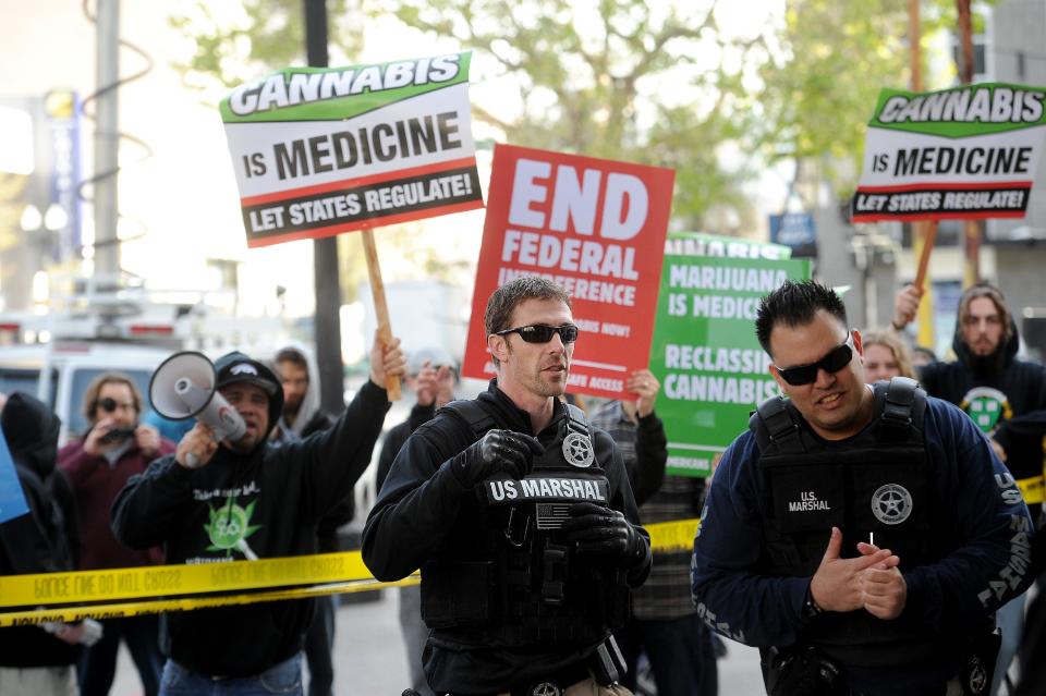 With marijuana proponents chanting behind them, U.S. marshals raid Oaksterdam University in Oakland, Calif., on Monday, April 2, 2012. The facility, one of several that federal agents raided on Monday, teaches people how to grow marijuana. (AP Photo/Noah Berger)