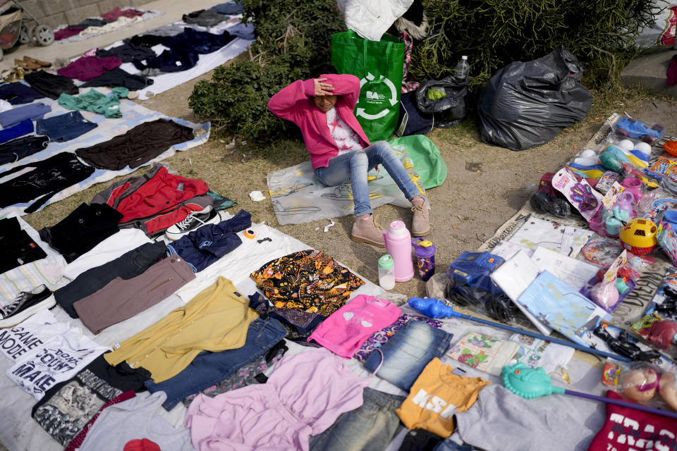 Una vendedora se sienta rodeada de sus prendas de segunda mano exhibidas en un mercado donde la gente puede comprar o intercambiar productos en las afueras de Buenos Aires, Argentina, el miércoles 10 de agosto de 2022. (AP Foto/Natacha Pisarenko)