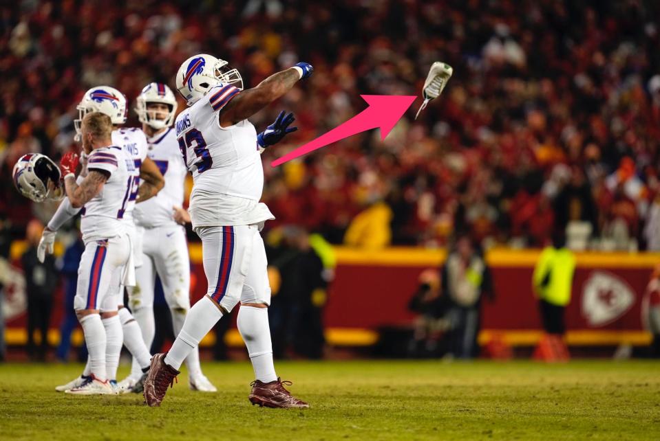 Bills offensive tackle Dion Dawkins flings a shoe left by the fan who ran onto the field.