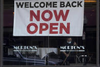 A sign reading "Welcome Back Now Open" is posted on the window of a Morton's Steakhouse restaurant as a man works inside during the coronavirus pandemic in San Francisco, Thursday, March 4, 2021. (AP Photo/Jeff Chiu)