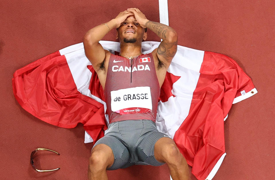 Andre De Grasse lies down on the track with his head in his hands after winning his first gold medal as an Olympian in Tokyo. 