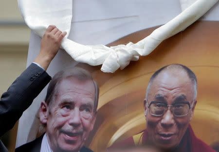 A man adjusts a ceremonial scarf on a poster of Tibet's exiled spiritual leader the Dalai Lama and late Czech President Vaclav Havel in Prague, Czech Republic, October 17, 2016. REUTERS/David W Cerny