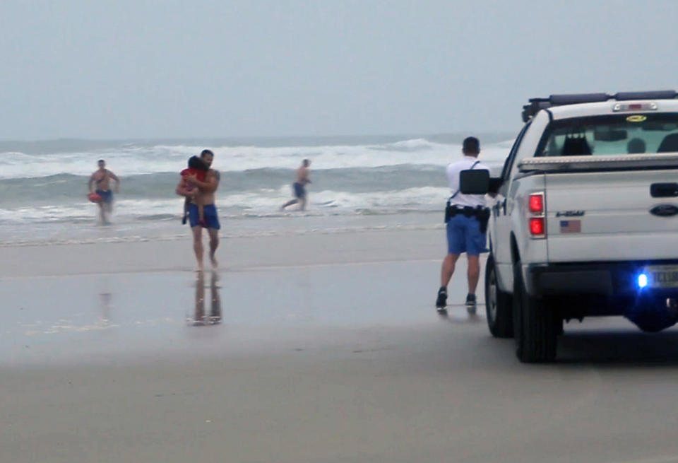 FILE - In this March 4, 2014 file image made from video, a lifeguard carries one of the three children rescued from a minivan that their mother, Ebony Wilkerson, drove into the Atlantic in Daytona Beach, Fla. Wilkerson as charged Friday with attempted first-degree murder and aggravated child abuse, though she has denied trying to harm anyone, authorities said. (AP Photo/Simon Besner, File) NO SALES