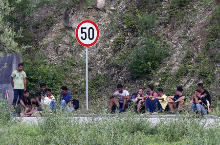 Migrants sit on the street next to the border between Bosnia and Herzegovina and Croatia in Velika Kladusa, picture taken from Maljevac, Croatia, June 18, 2018. REUTERS/Antonio Bronic