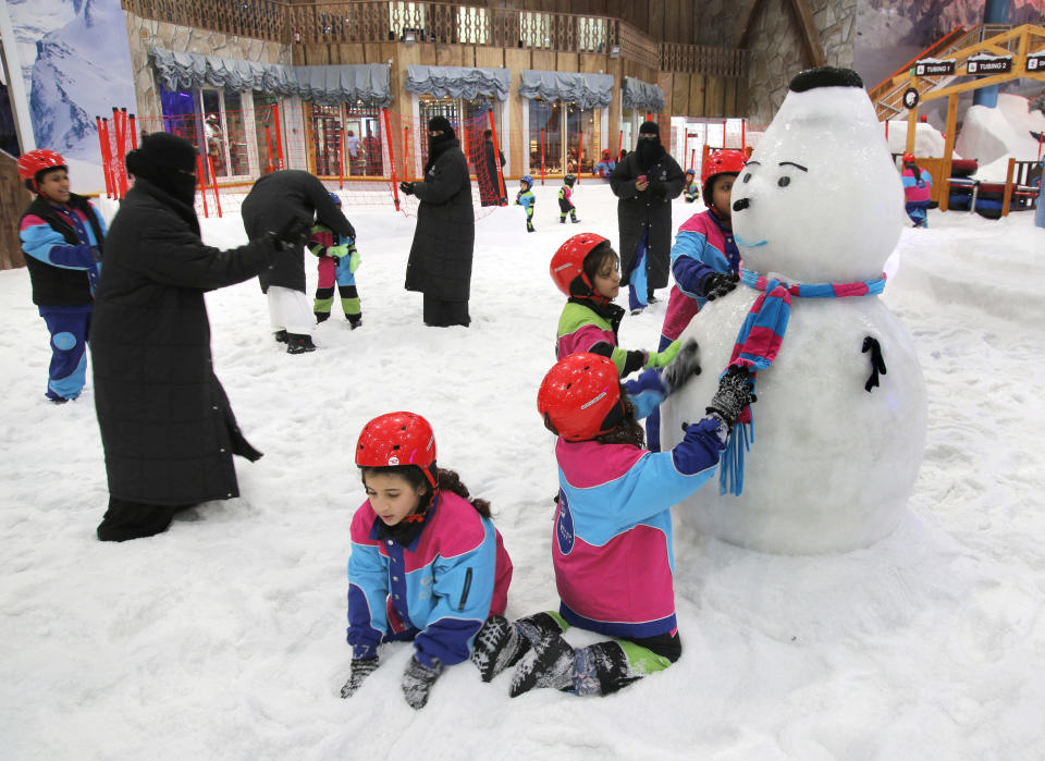 FILE - In this March 9, 2018 file photo, children play by snow at the "Snow City" in the Othaim Mall, in Riyadh, Saudi Arabia. King Salman has extended monthly allowances for government employees, military personnel, pensioners, social security recipients and students into next year. The announcement, carried by the Saudi Press Agency on Tuesday, Dec. 18, 2018, comes on the same day the kingdom's 2019 budget is scheduled to be unveiled. (AP Photo/Amr Nabil)