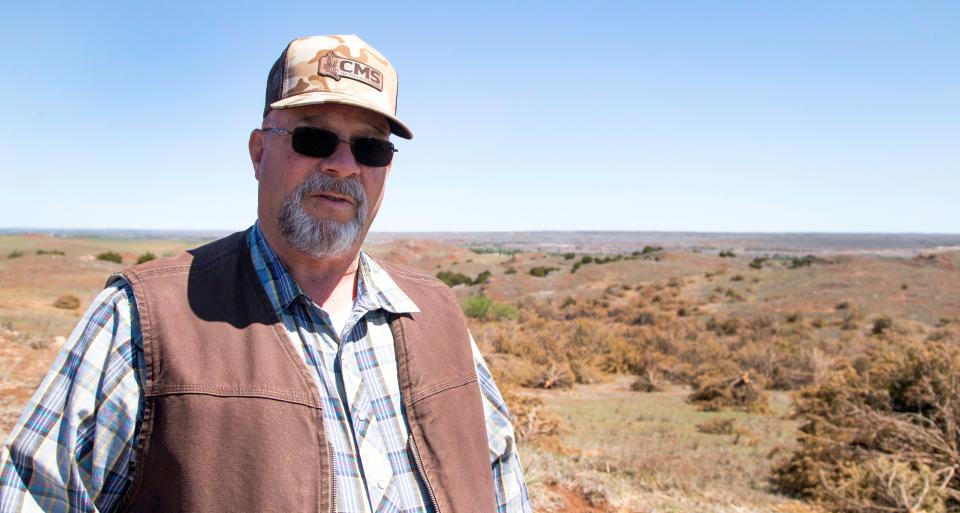 Jimmy Emmons talks about redcedar encroachment on the hill at his ranch near Leedey, where acres of trees have been cut by a mulching company.