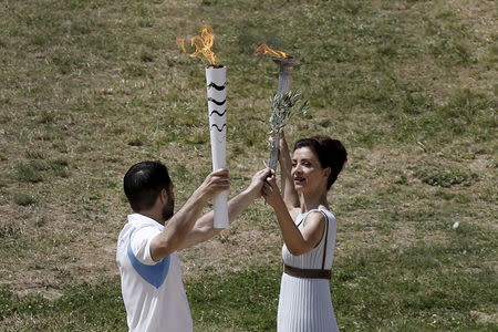 Greek actress Katerina Lehou, playing the role of High Priestess, passes the Olympic flame to a volunteer filling in for the first torch bearer, during the dress rehearsal for the Olympic flame lighting ceremony for the Rio 2016 Olympic Games at the site of ancient Olympia in Greece. REUTERS/Alkis Konstantinidis