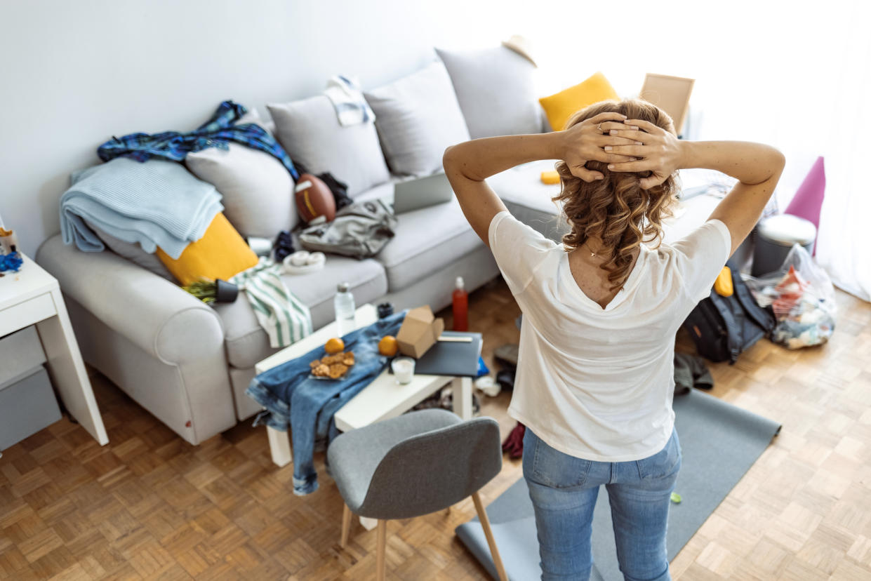 A woman looking at a cluttered living space.