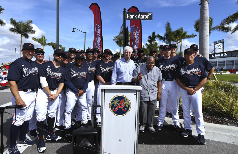 Atlanta Braves Chairman Terry McGuirk, center, and members of the Atlanta Braves baseball team honor baseball Hall of Famer Hank Aaron, third from right, front, with a street named after him outside CoolToday Park, the spring training baseball facility of the Braves, in North Port, Fla., Tuesday, Feb. 18, 2020 (Curtis Compton/Atlanta Journal-Constitution via AP)