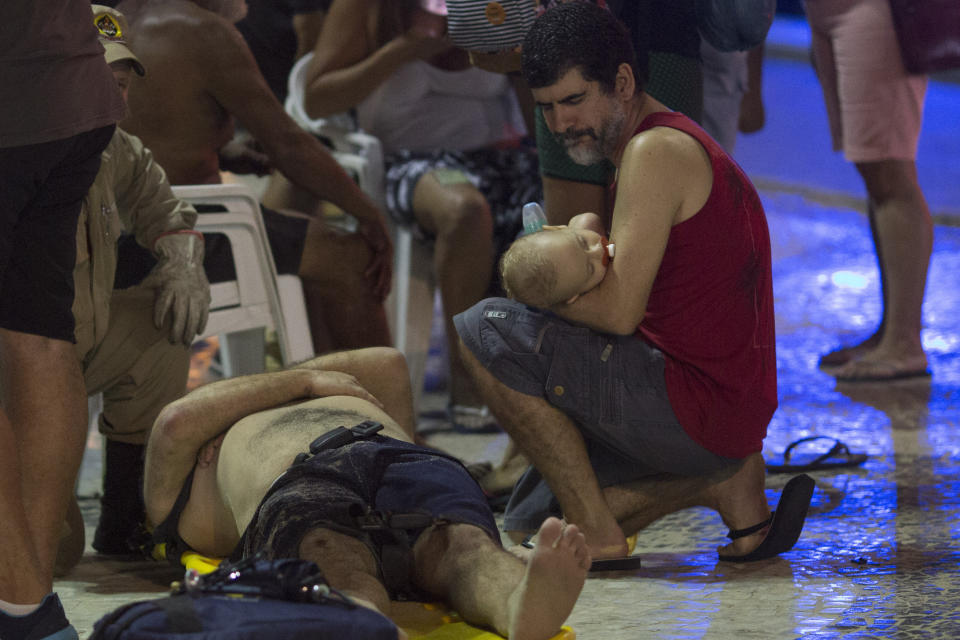 <p>A man holds a baby next to an injured man after a car drove into the crowded seaside boardwalk along Copacabana beach in Rio de Janeiro, Brazil, Thursday, Jan. 18, 2018. (Photo: Silvia Izquierdo/AP) </p>