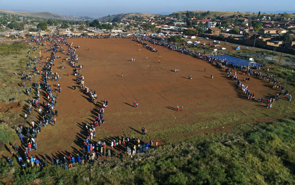 Centenares de personas hacen fila para recolectar alimentos en un centro de distribución en el asentamiento informal de Itereleng en Pretoria, Sudáfrica, el miércoles 20 de mayo de 2020, cuando el país cumplía 55 días de confinamiento soocial ordenado por el gobierno para evitar la propagación del coronavirus. (AP Foto/Phil Magakoe)