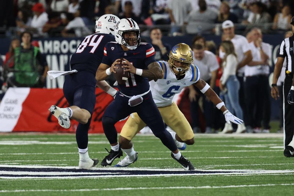 Nov 4, 2023; Tucson, Arizona, USA; Arizona Wildcats quarterback Noah Fifita #11 makes a pass under pressure against UCLA Bruins quarterback Justyn Martin #6 during the first half at Arizona Stadium. Mandatory Credit: Zachary BonDurant-USA TODAY Sports