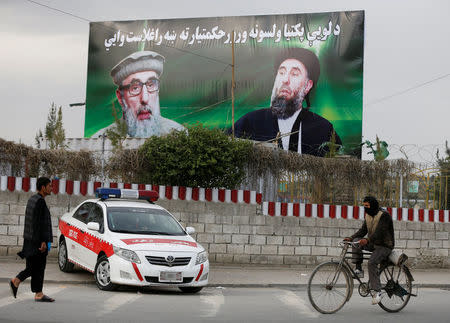 An Afghan man rides on his bicycle past a banner with pictures of Afghan warlord Gulbuddin Hekmatyar in Kabul, Afghanistan May 2, 2017. Picture taken May 2, 2017. REUTERS/Omar Sobhani