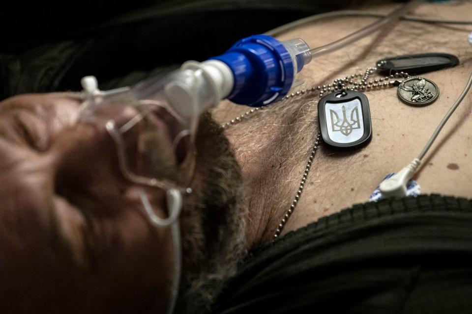 A wounded Ukrainian soldier wears an identification tag with a trident, the coat of arms of Ukraine, while being transported from a battlefield area to a hospital on a medical evacuation bus in eastern Ukraine on Feb. 22, 2023. (John Moore/Getty Images)