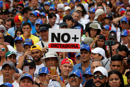 Demonstrators hold placard that reads: 'No more dictatorship' while rallying against Venezuela's President Nicolas Maduro in Caracas, Venezuela May 1, 2017. REUTERS/Carlos Garcia Rawlins